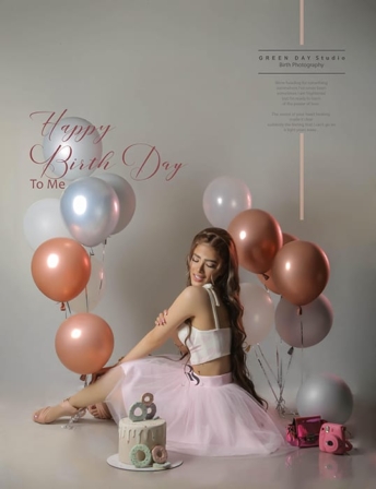 Woman in a pink skirt seated among pink, rose-gold and silver balloons during a birthday portrait session