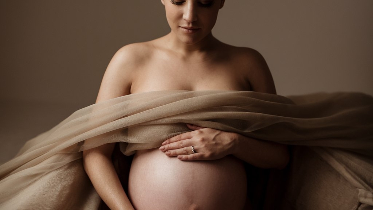 Artistic maternity photography in a Toronto studio showing a pregnant woman with visible baby bump and soft professional lighting