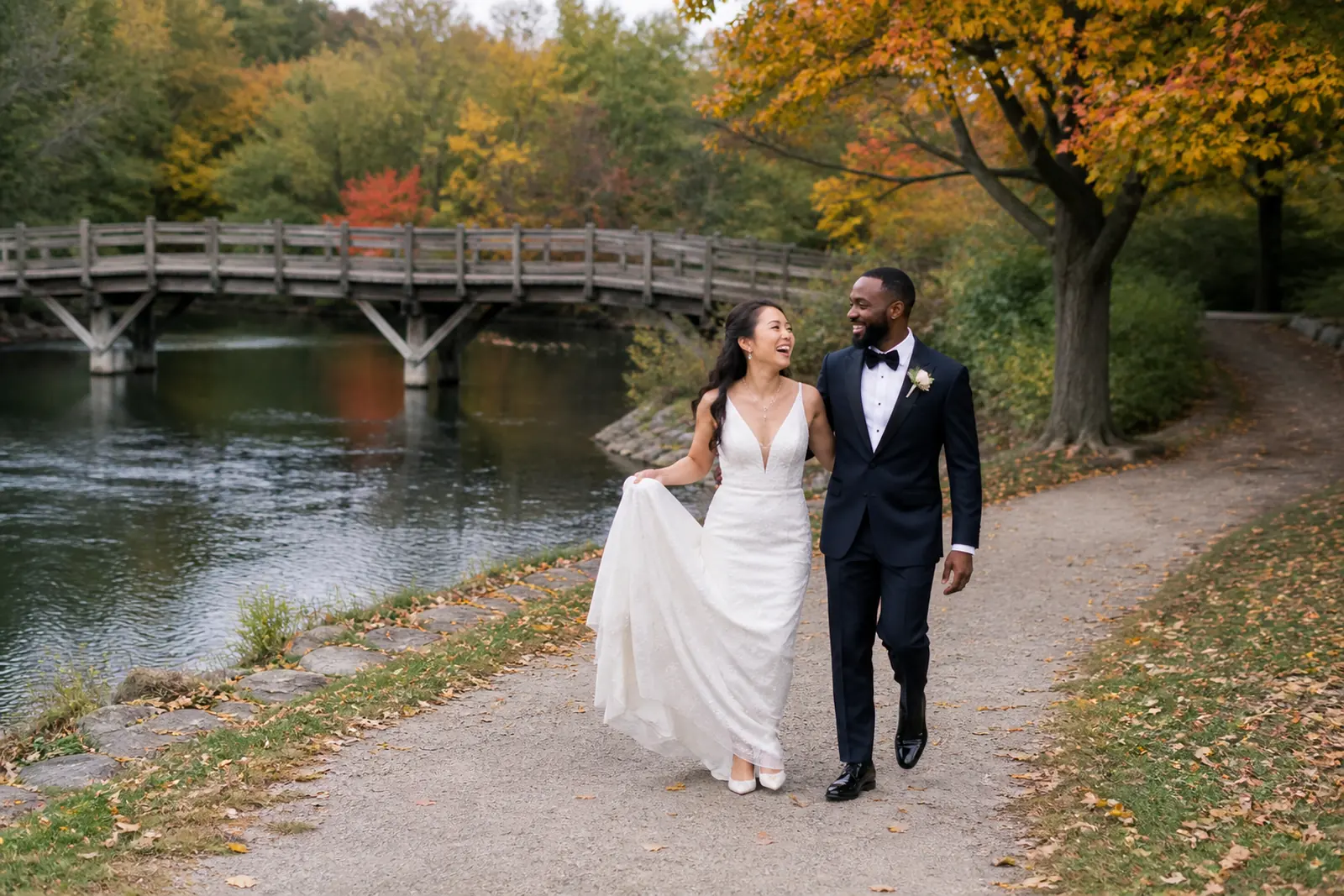Newlywed couple walking beside Mill Pond in Richmond Hill during autumn golden hour