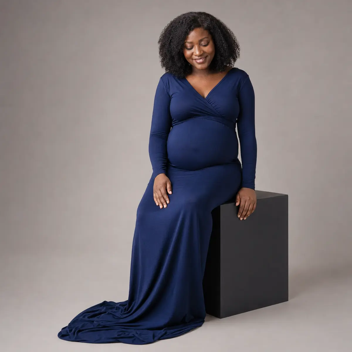 Seated studio maternity portrait with natural posing and soft light