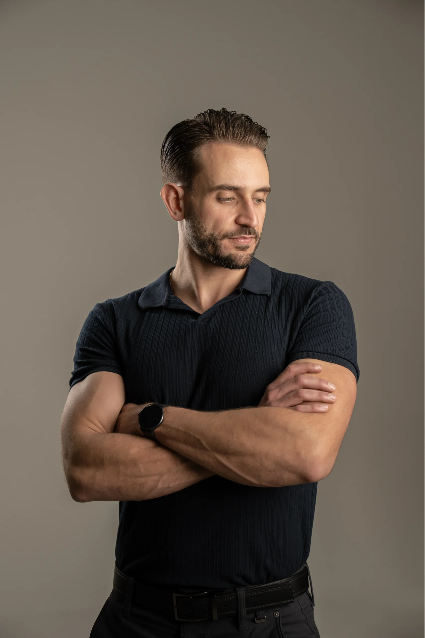 Male professional with folded arms photographed against a neutral studio background