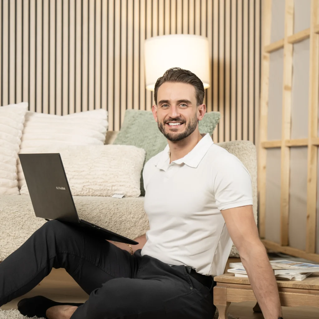 Personal branding portrait of a smiling man seated with a laptop