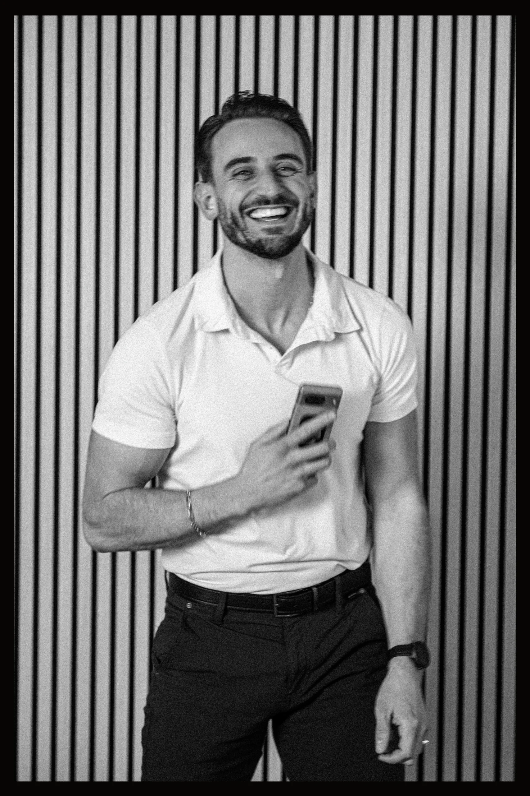 Candid black-and-white portrait of a smiling male professional holding a phone