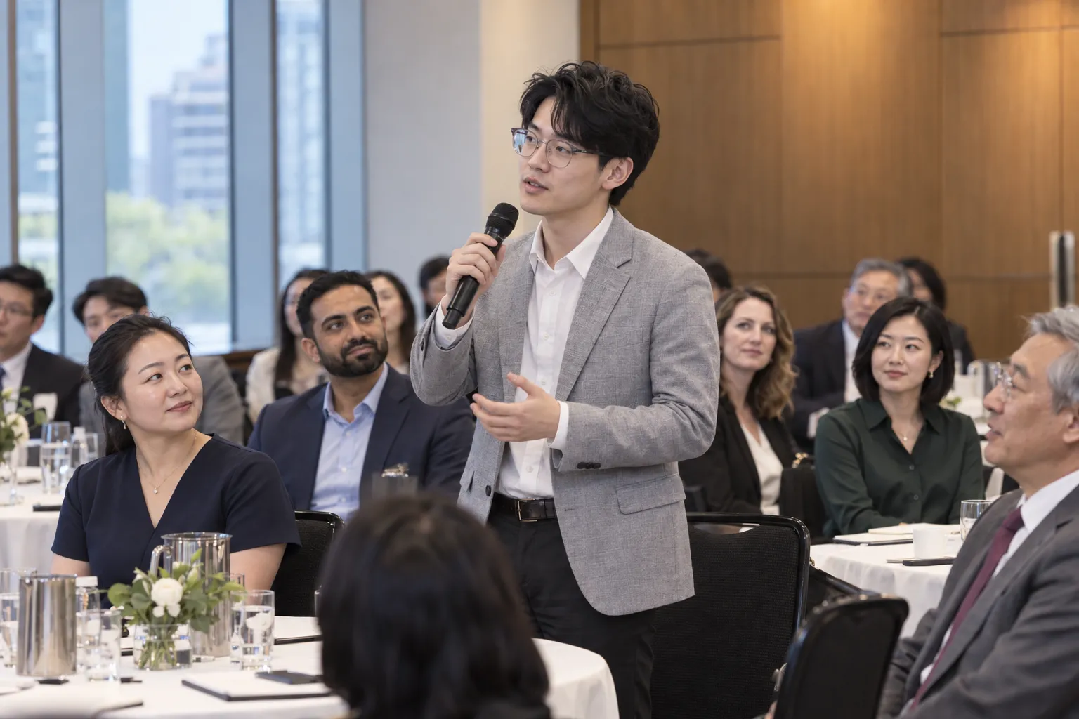 Standing attendee speaking into a handheld microphone among seated guests